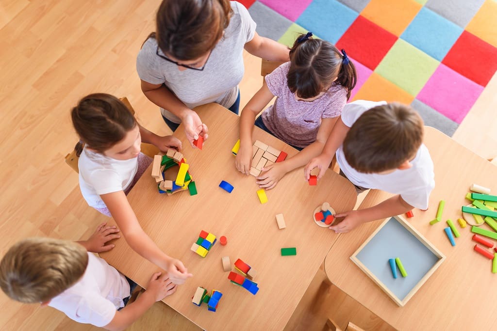 Preschool teacher with children playing with colorful wooden did