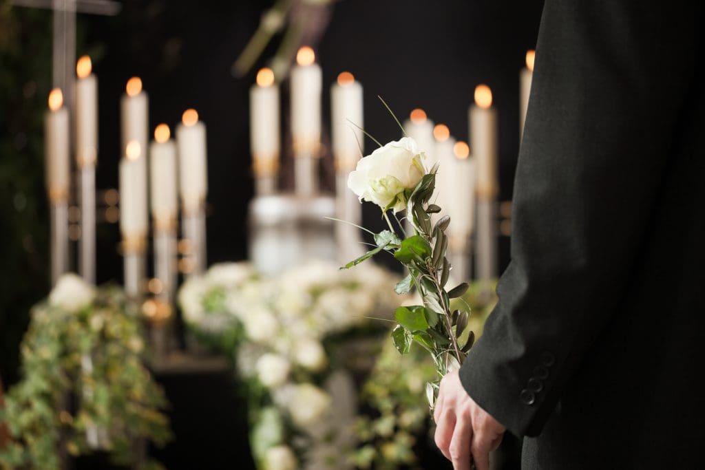 Man in suit holding white rose in funeral