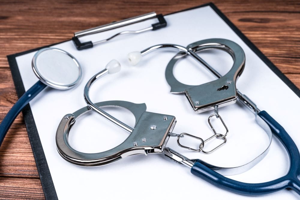 Handcuffs around a stethoscope representing a nurse with criminal charges.